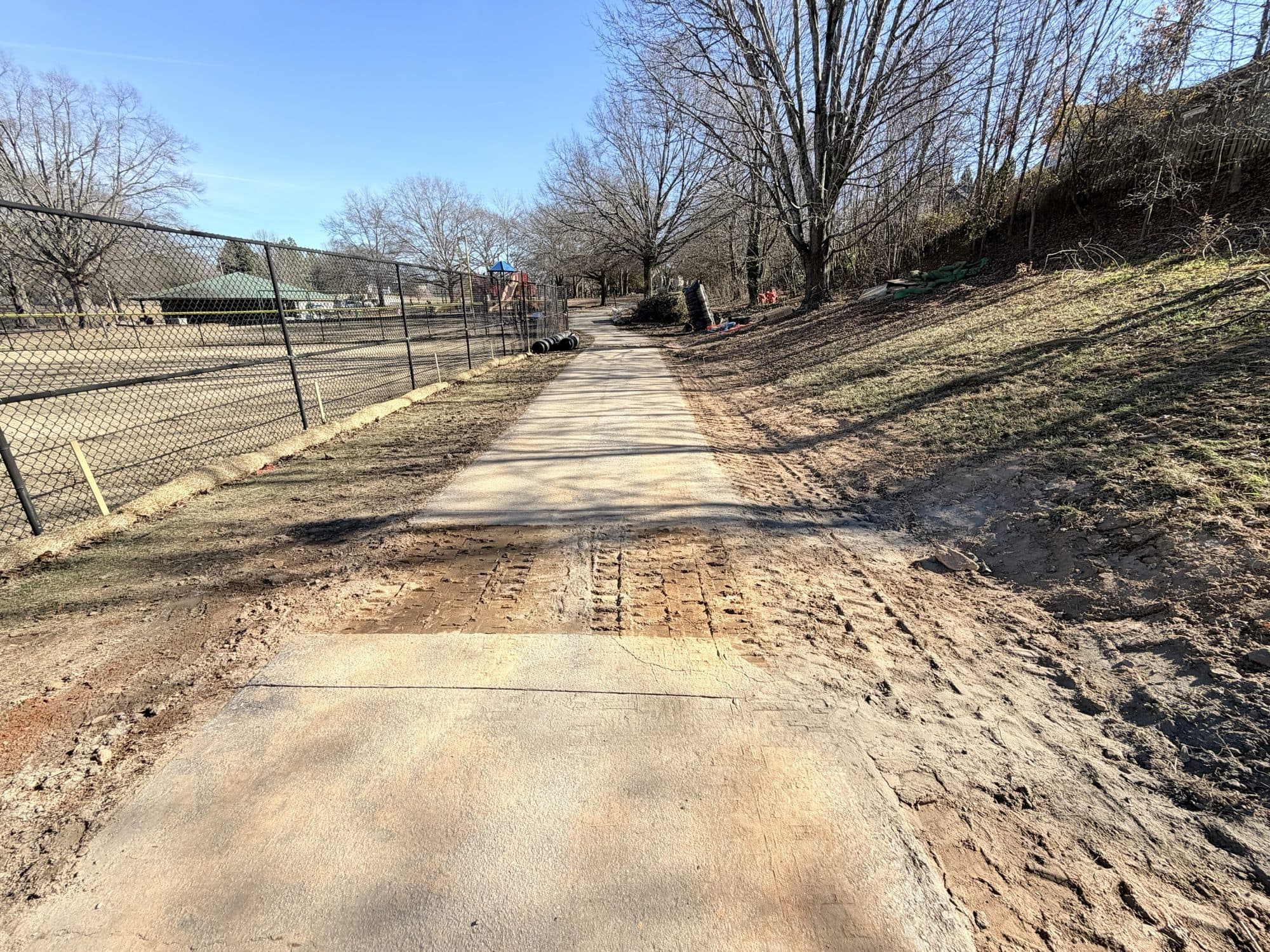 The lower run of the concrete flume alongside the park trail, with the tennis courts and playground beyond