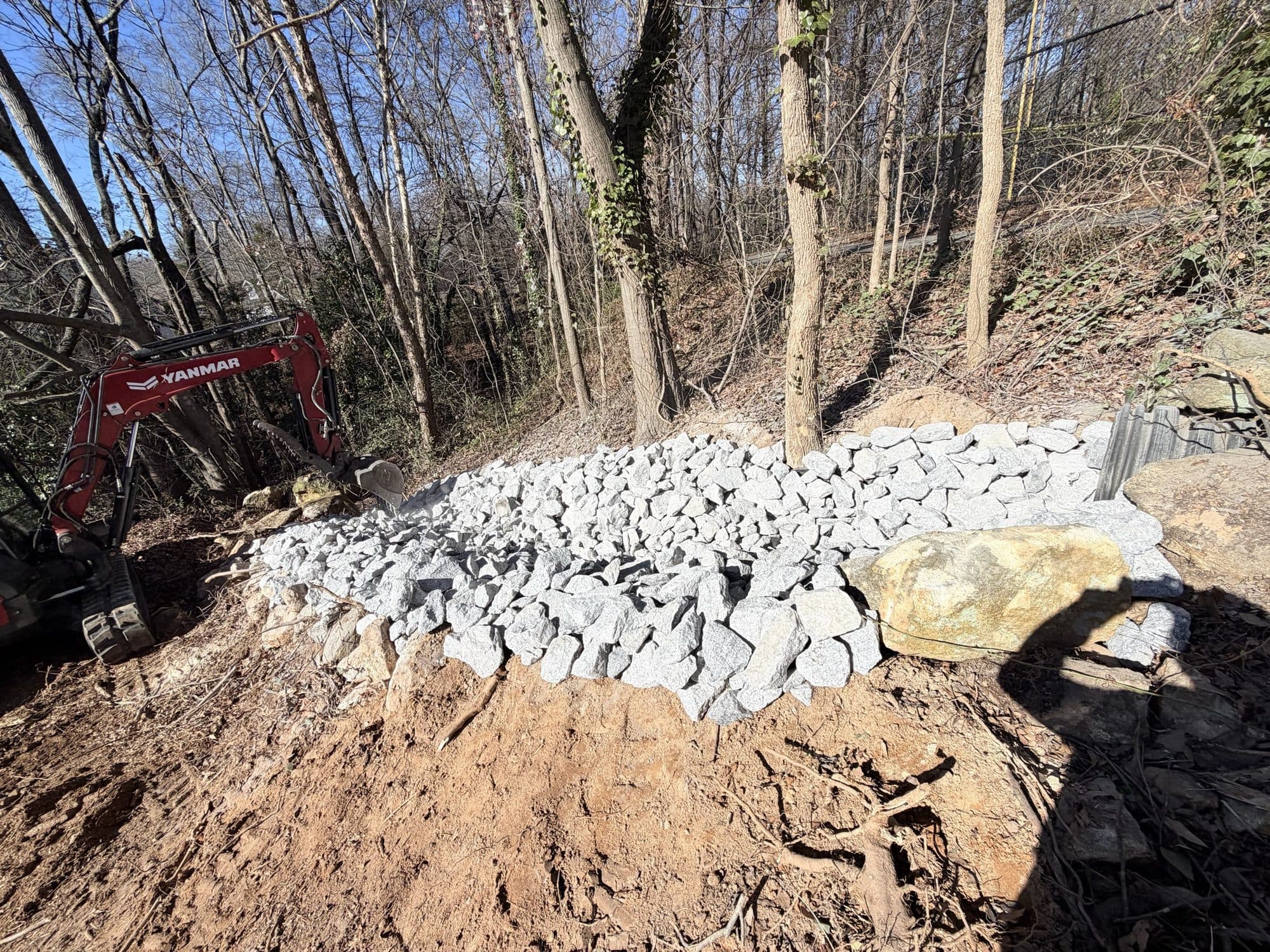 Riprap placed at the outfall in the tree line to protect the discharge point from scour