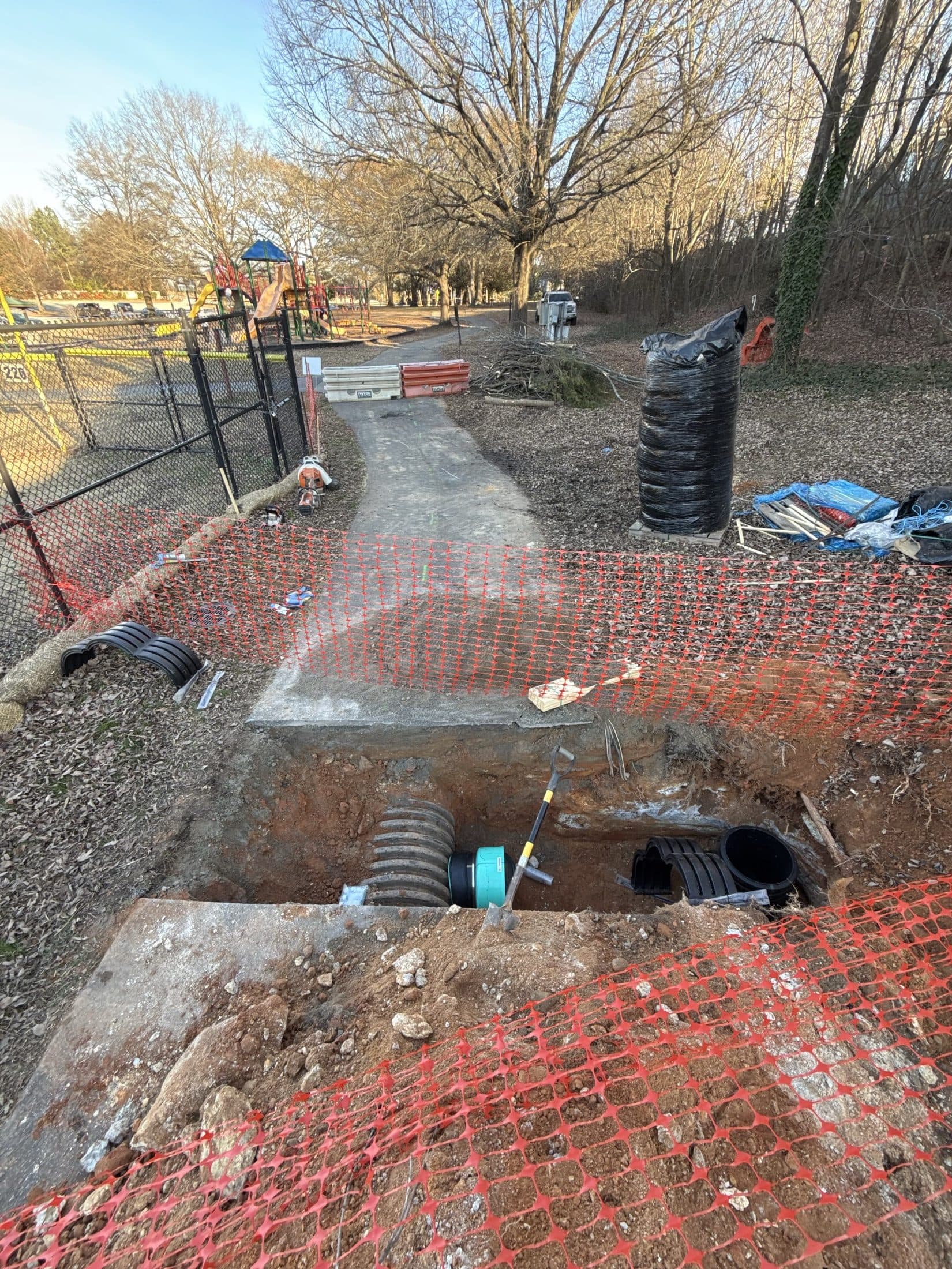 Open excavation for a drainage structure, fenced off from the playground with safety barrier