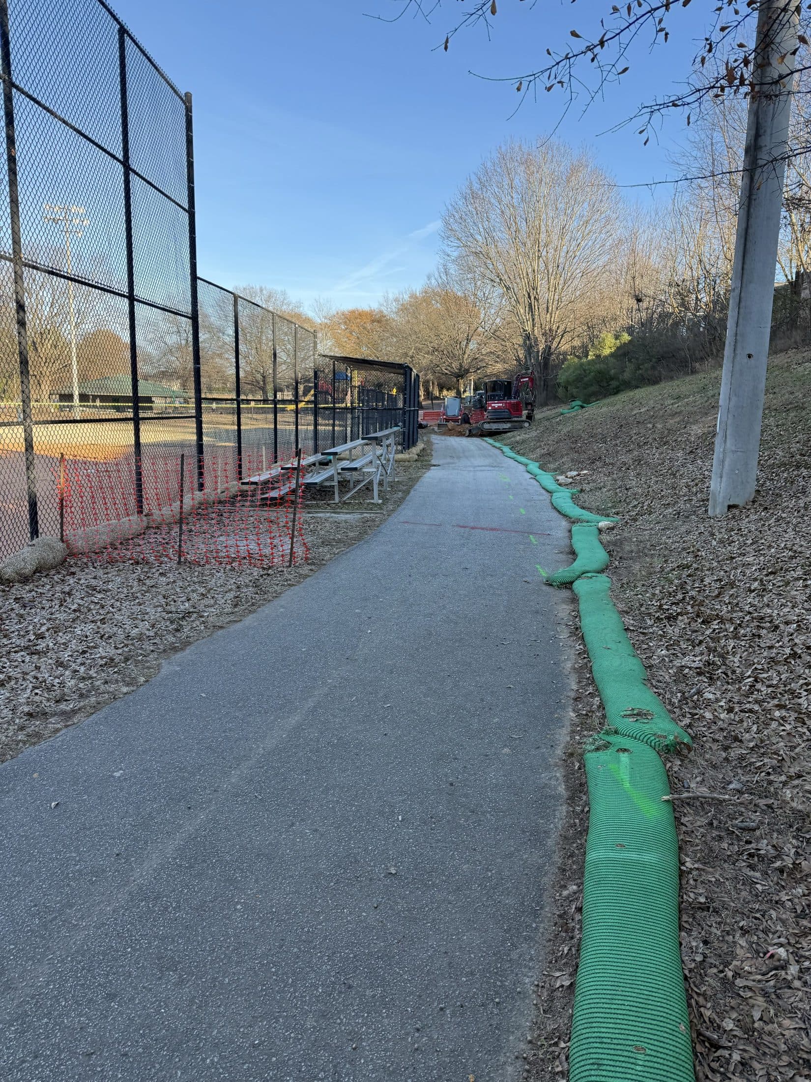 The finished trail running between the ball field backstop and the park tree line