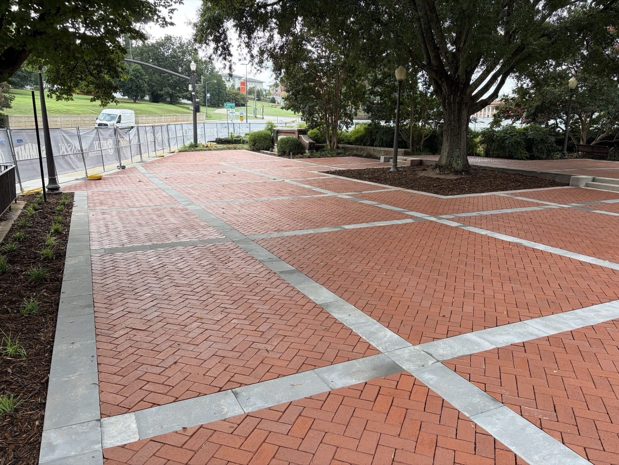 The finished Mell Hall brick plaza at Clemson University, clay pavers in herringbone within concrete banding around a mature tree