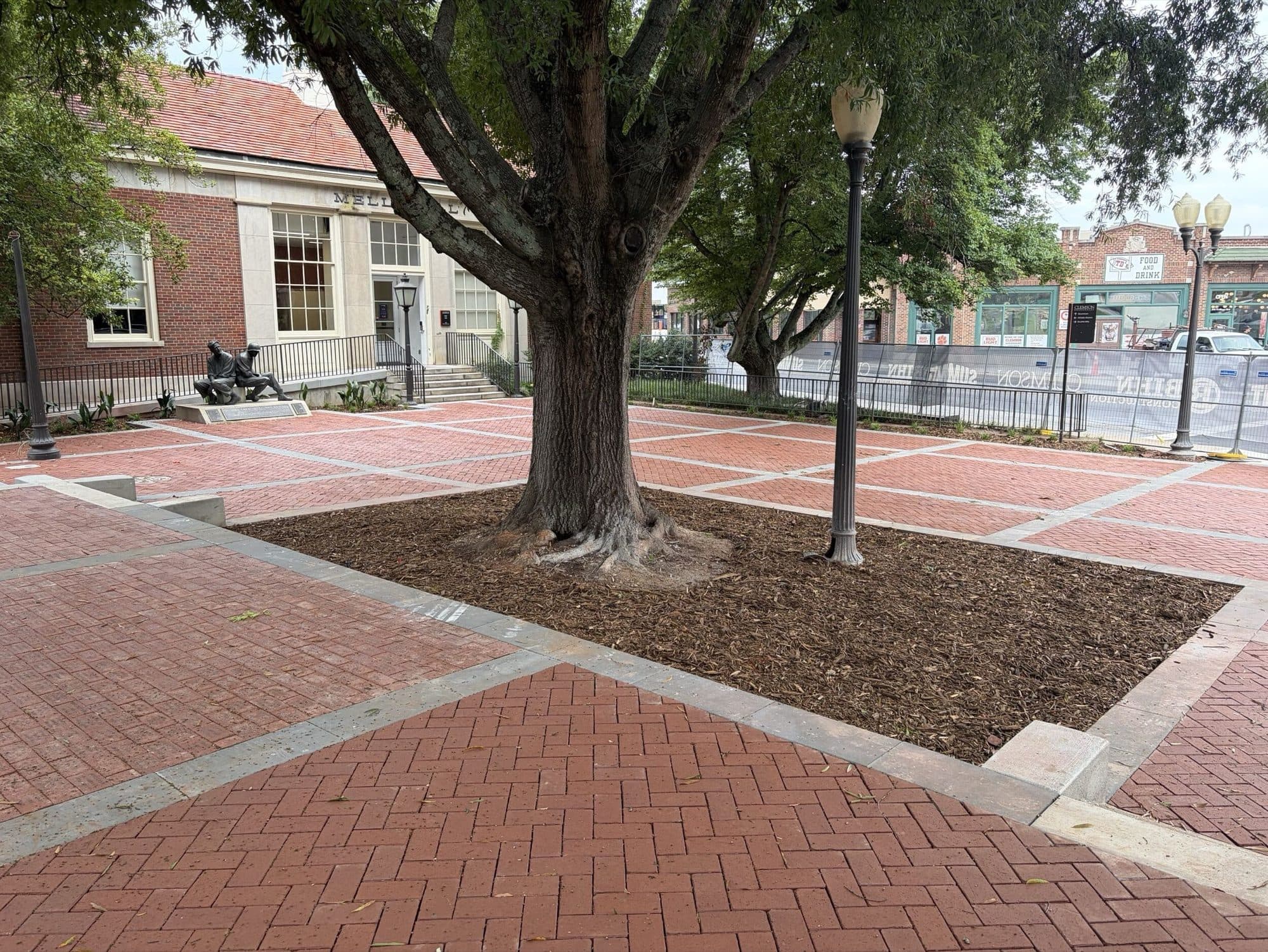 A mature tree left in place within a mulched well cut into the finished paver field