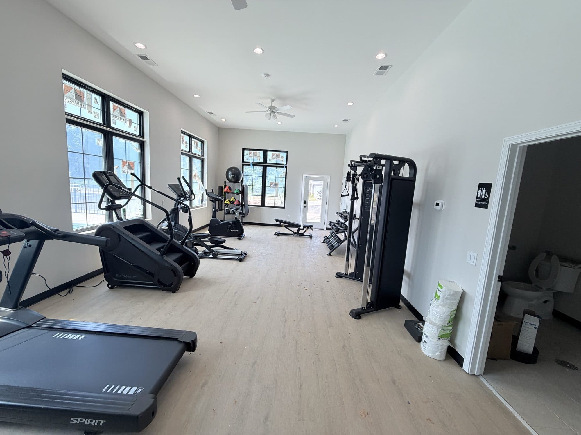 The finished fitness room with plank flooring, recessed lighting, and equipment in place