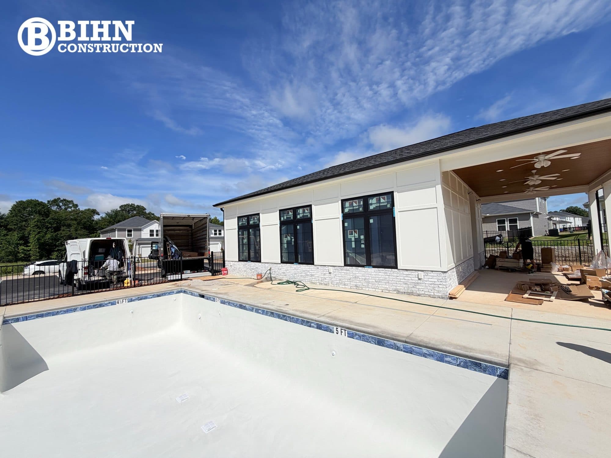 The finished clubhouse exterior with the plastered pool shell and concrete deck complete in front of it