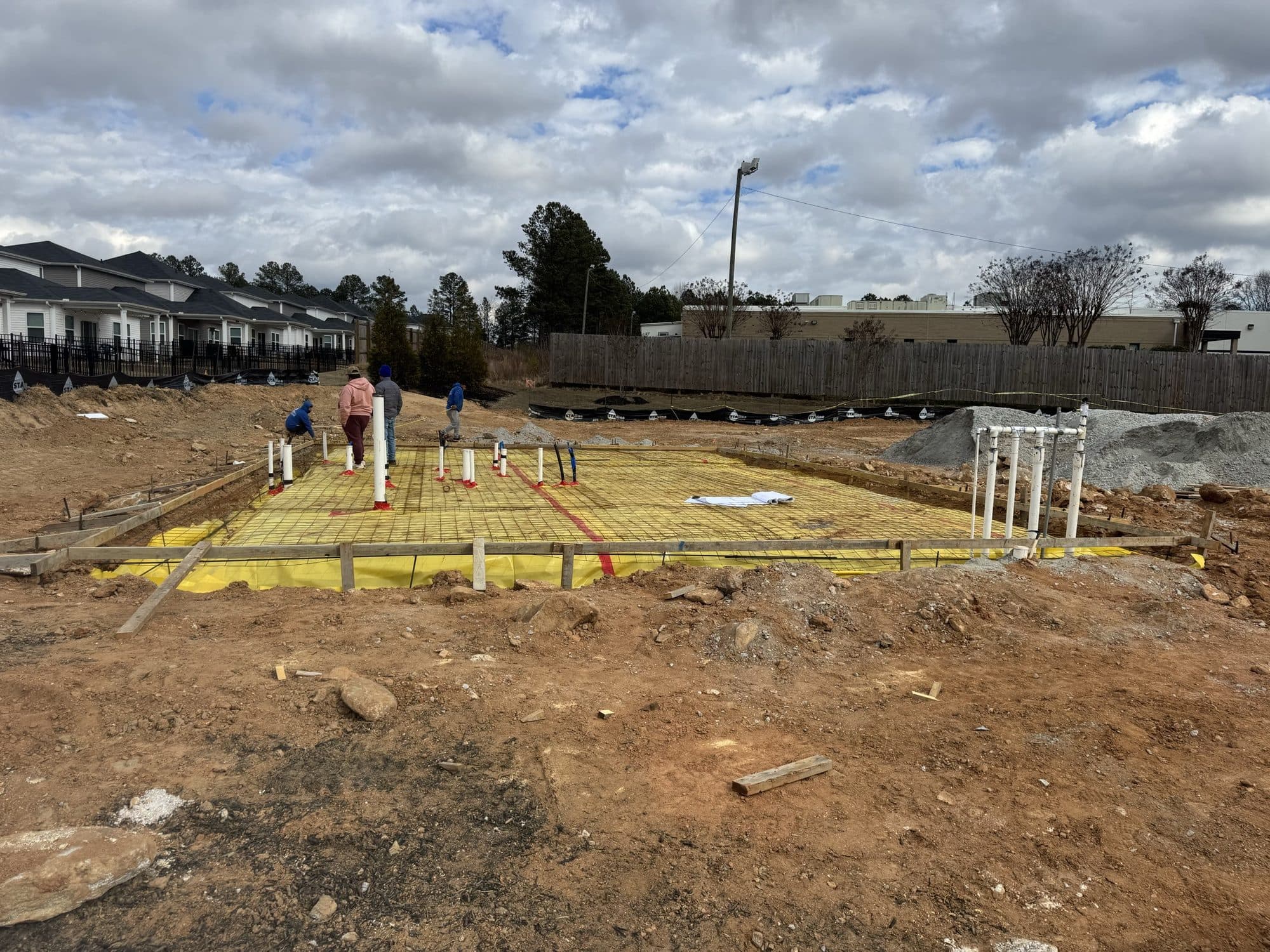 The clubhouse slab prepared with vapor barrier, reinforcing mesh, and plumbing stub-ups before the pour