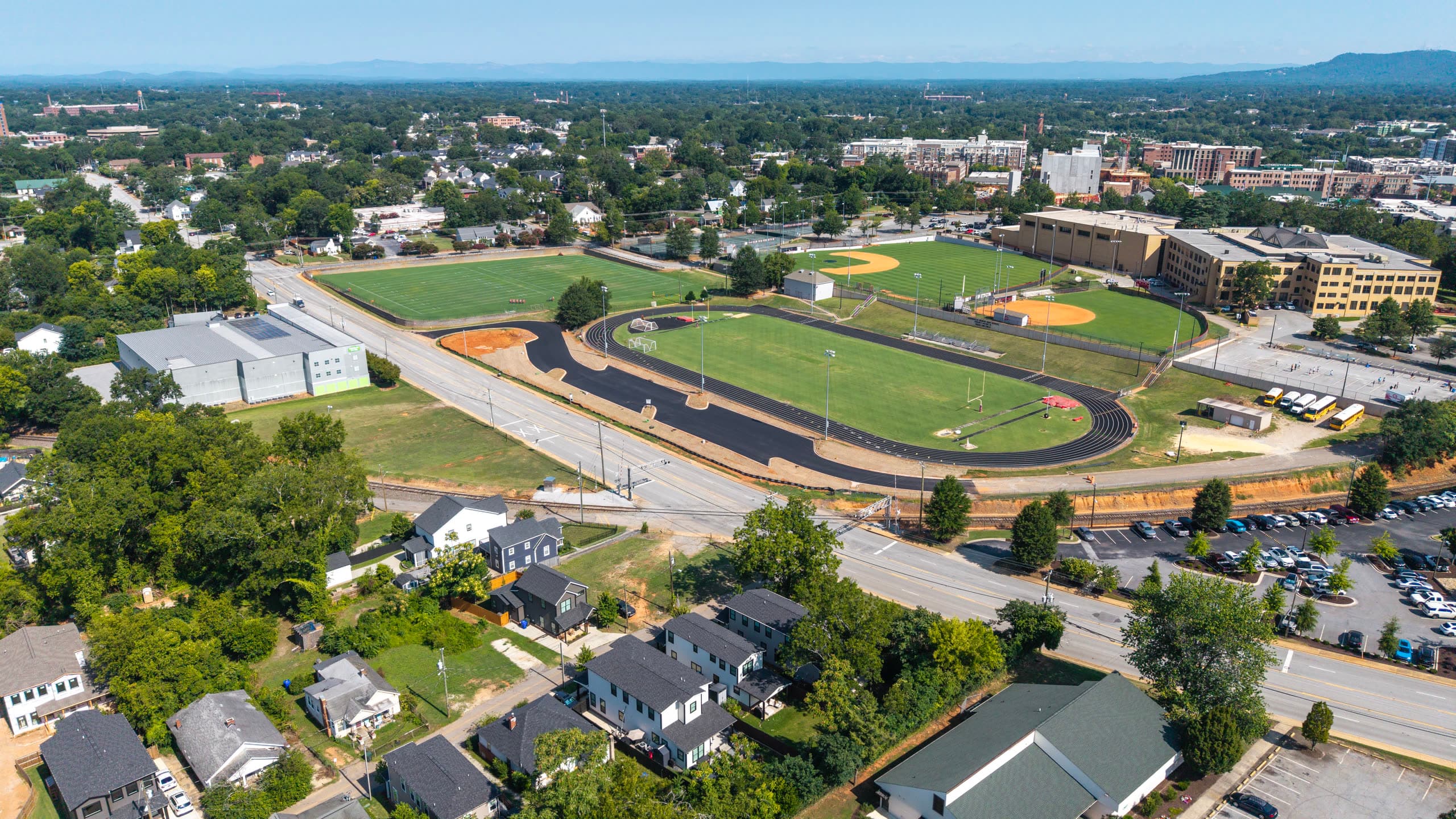 Wide aerial of the Greenville Senior High School campus, athletic fields, and the new parking lot in context