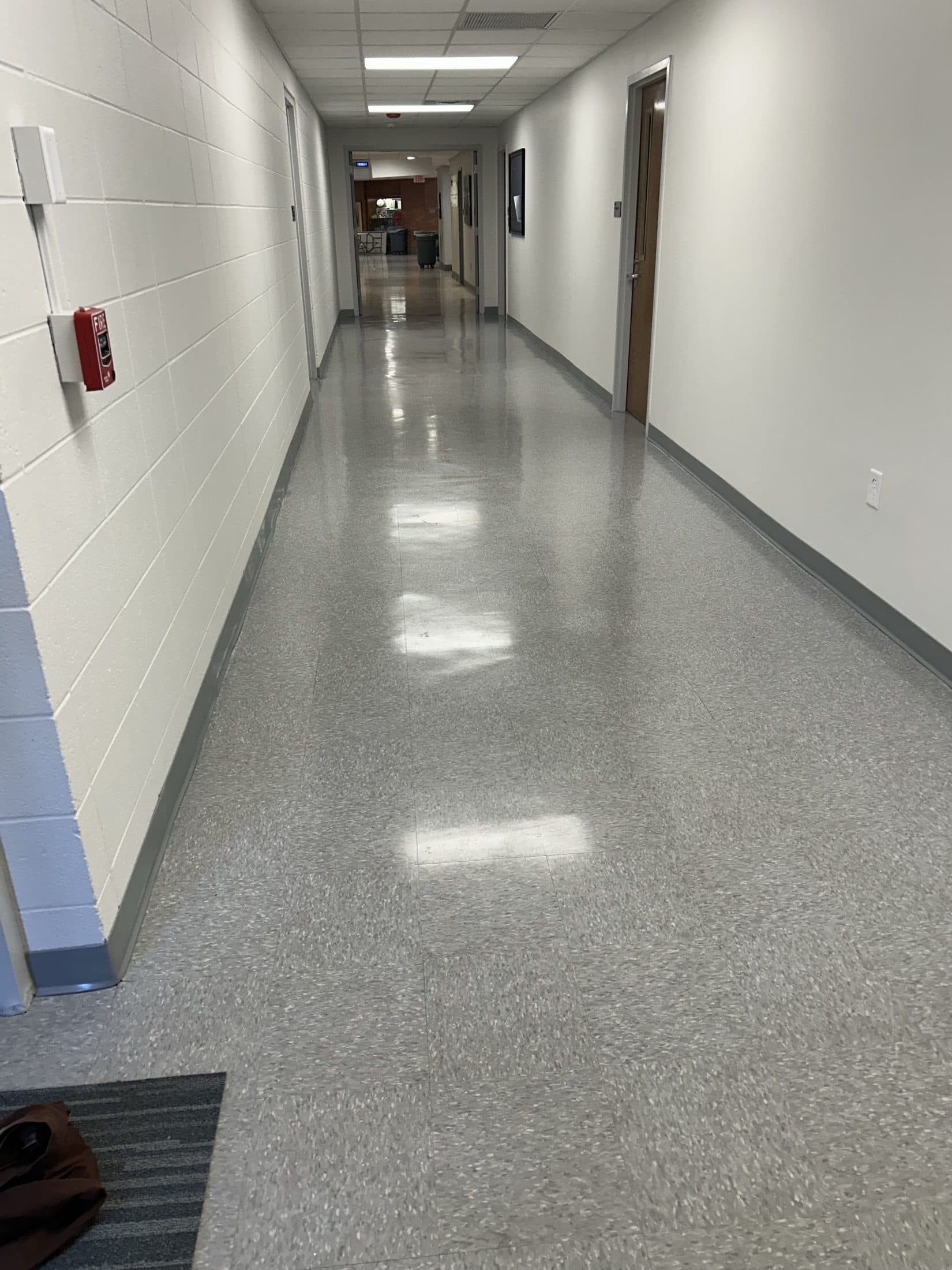 The finished campus corridor with new resilient tile flooring, painted block, a new ceiling grid, and LED lighting