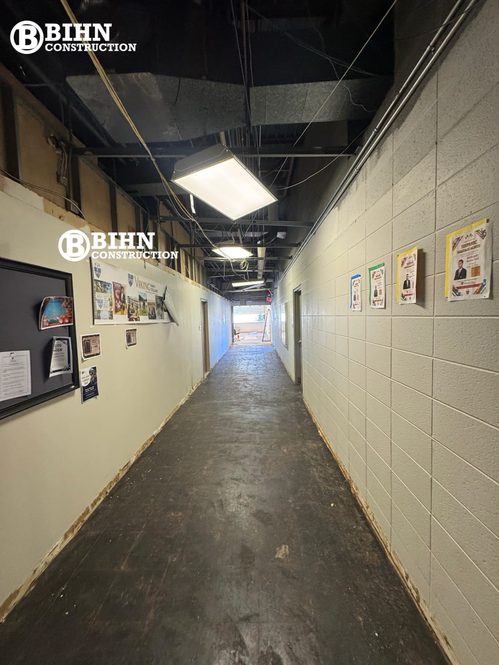 The corridor mid-demolition with the ceiling out, wiring exposed, and the original worn floor still down