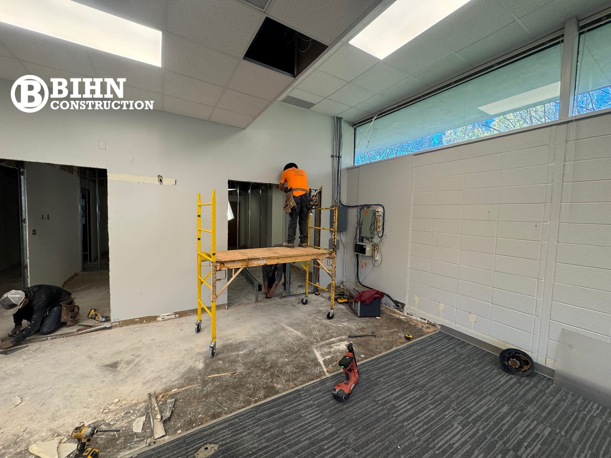 Crew working on ceilings and finishes in the renovated office suite with new clerestory glazing above