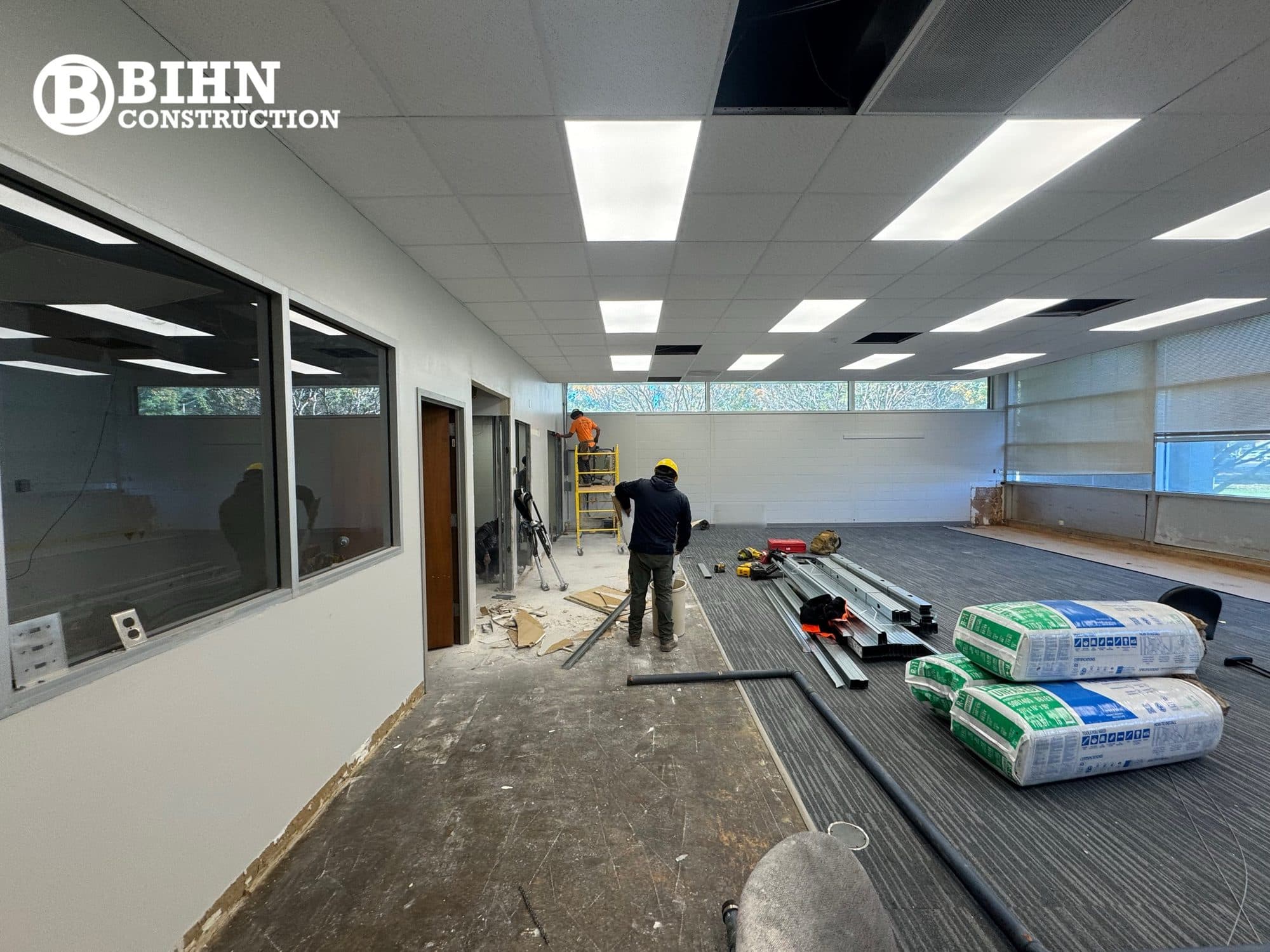 Carpet tile being laid in the finished office suite with new interior glazing and lighting complete
