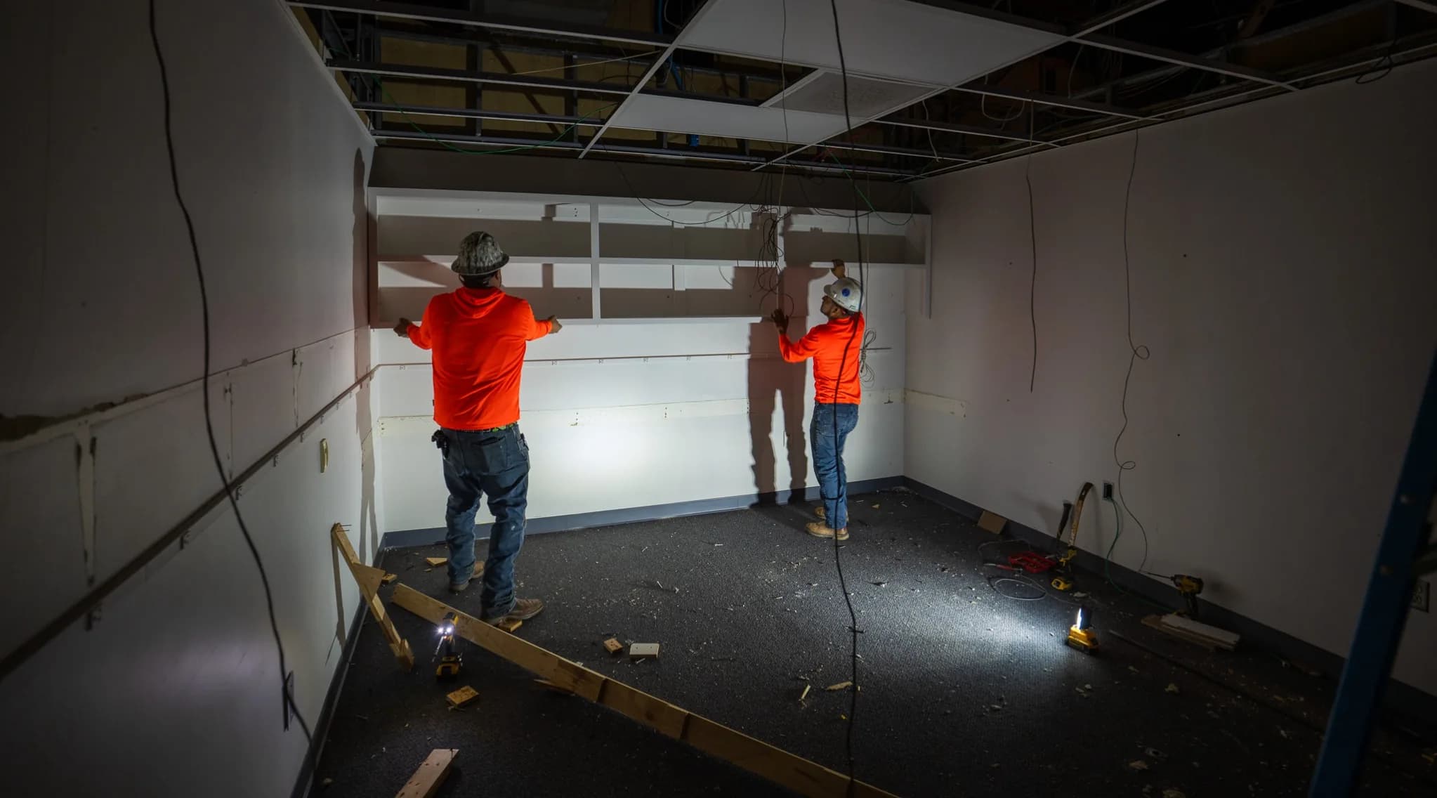 A Bihn Construction crew setting interior wall panels under a suspended ceiling grid on a commercial buildout